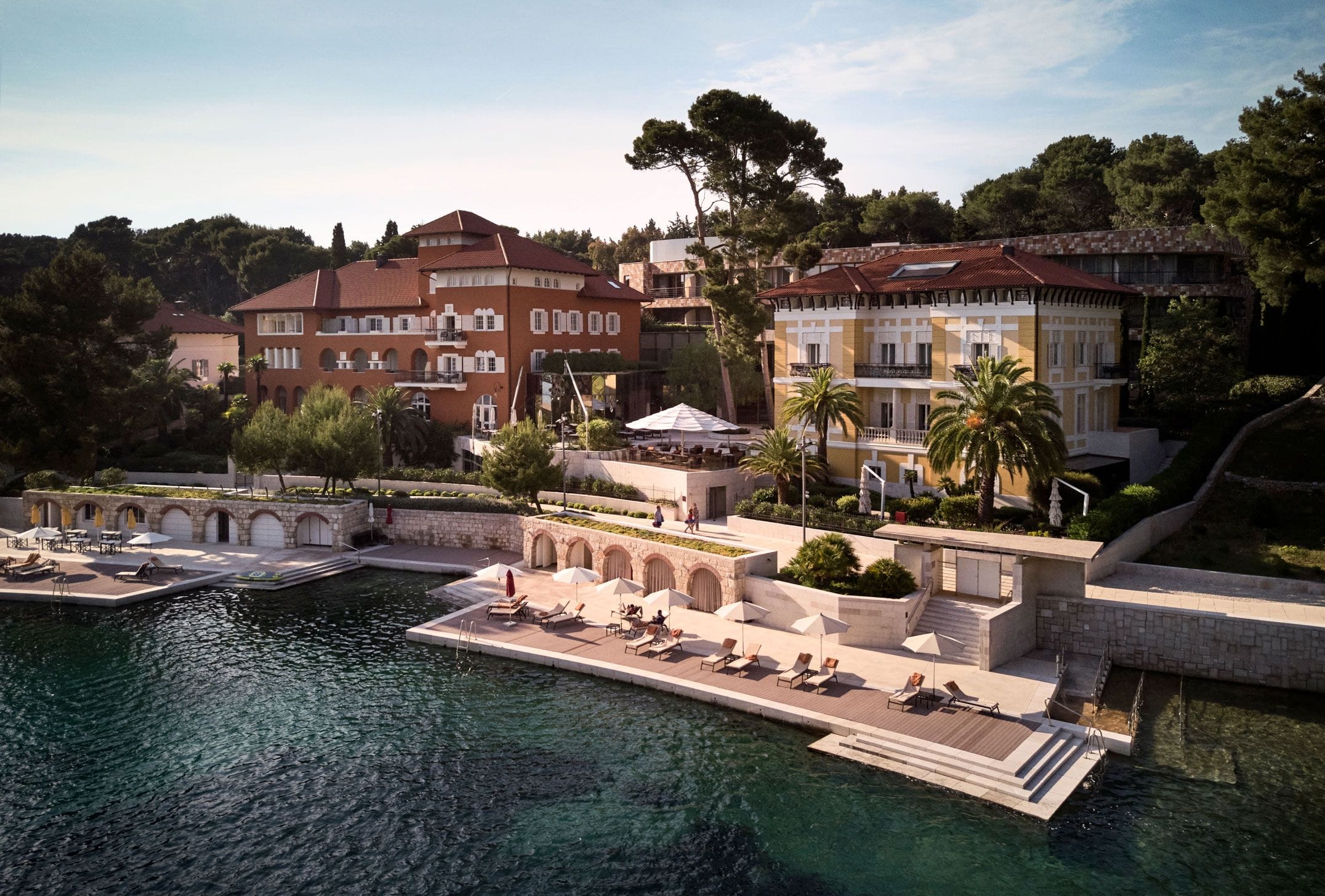 An aerial view of Alhambra and a nearby villa with a dock and sun loungers overlooking the calm waters