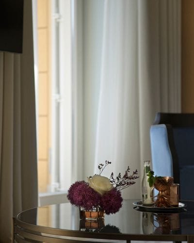 Elegant table setup with floral arrangement and decorative items in a room with sheer curtains and natural light
