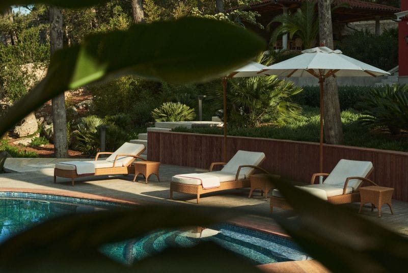 Poolside loungers under umbrellas surrounded by lush greenery, offering a tranquil spot for relaxation